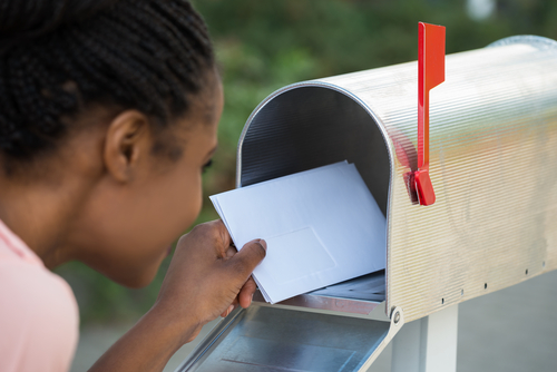 Girl placing a letter inside a mailbox