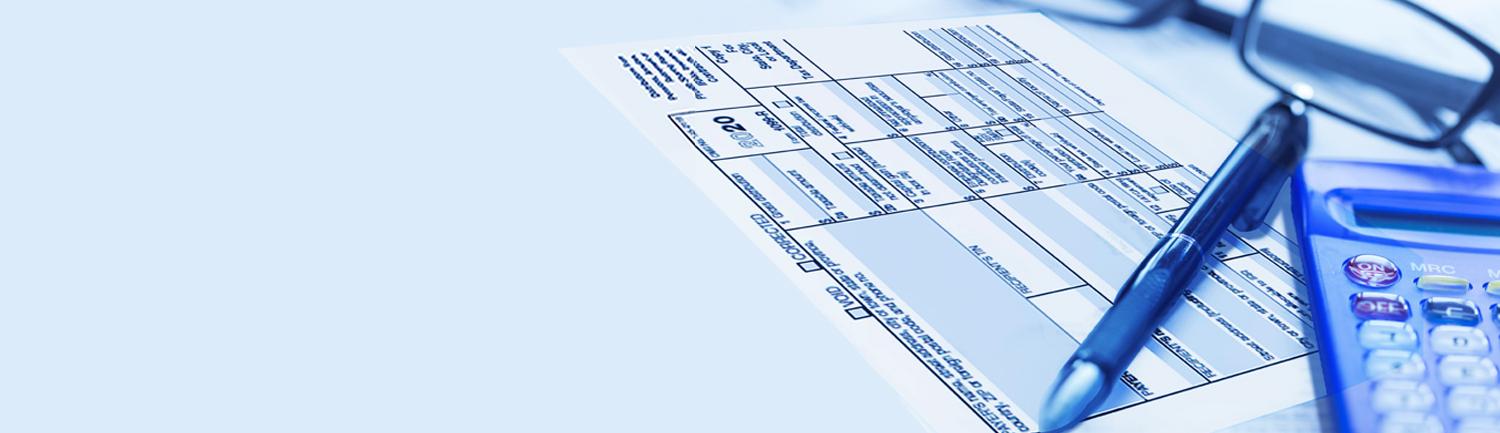 close-up of 1099-R tax form, pen, glasses, and a calculator. 